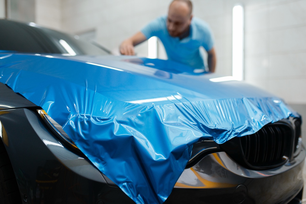 Paint Protection Film specialists installing a blue colored paint protection film onto a vehicle