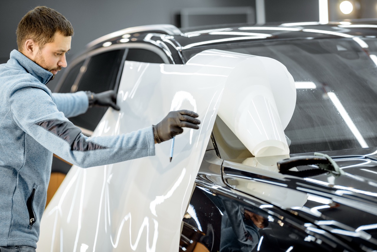 Paint protection film specialist installing white matte PPF onto a vehicle