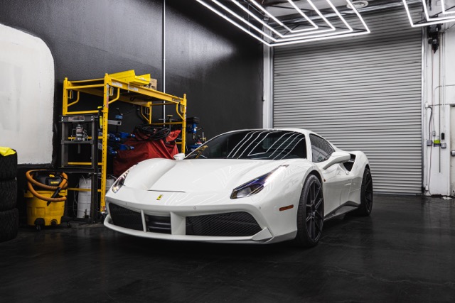 A white Ferrari vehicle inside of a shop