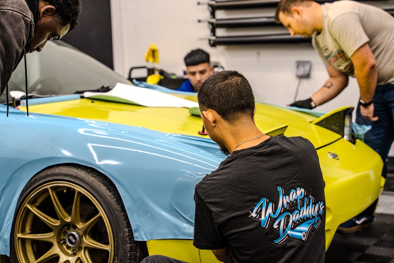 A group of Wrap Daddy's students installing vinyl onto a vehicle
